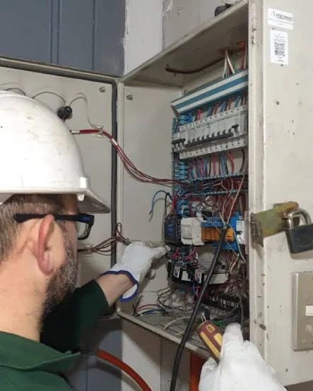 Técnico con casco y guantes dieléctricos interviniendo un gabinete eléctrico mural.