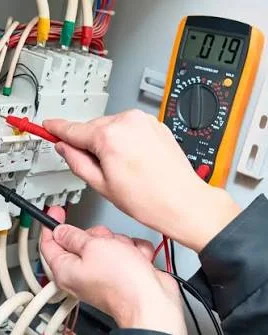 Puntas de prueba de un multímetro digital apoyadas sobre los bornes de un interruptor automático.