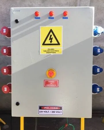 Tablero eléctrico con señalética de peligro, parada de emergencia y rotulación de tensión 220 y 380 volts.